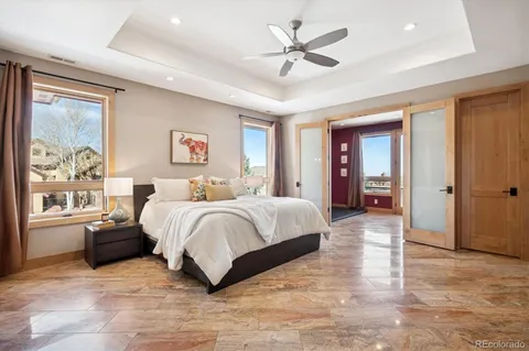 a spacious bedroom with a large bed a chandelier and windows