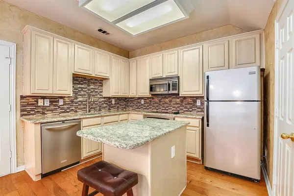 a kitchen with stainless steel appliances granite countertop a refrigerator a stove a sink and a refrigerator