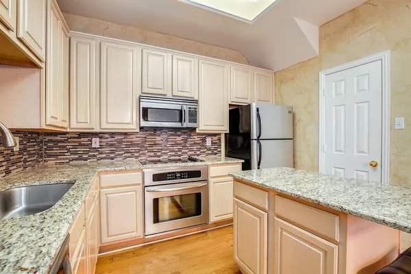 a kitchen with granite countertop a refrigerator stove and sink