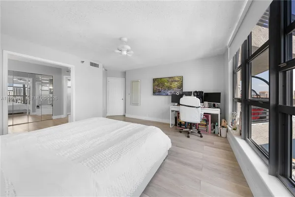 a spacious bedroom with a bed a table and large windows