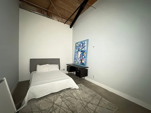 a bedroom with a bed and a painting on the wall