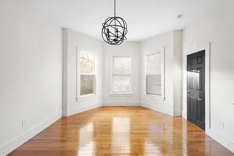 a view of an empty room with window and wooden floor