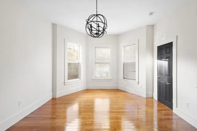 a view of an empty room with window and wooden floor