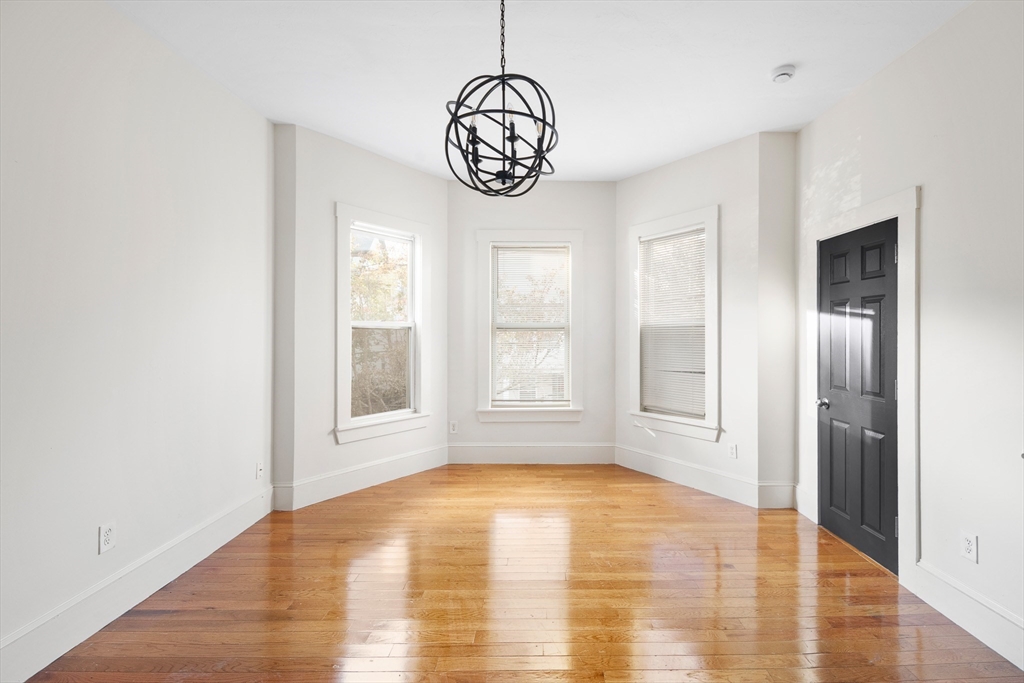 a view of an empty room with window and wooden floor