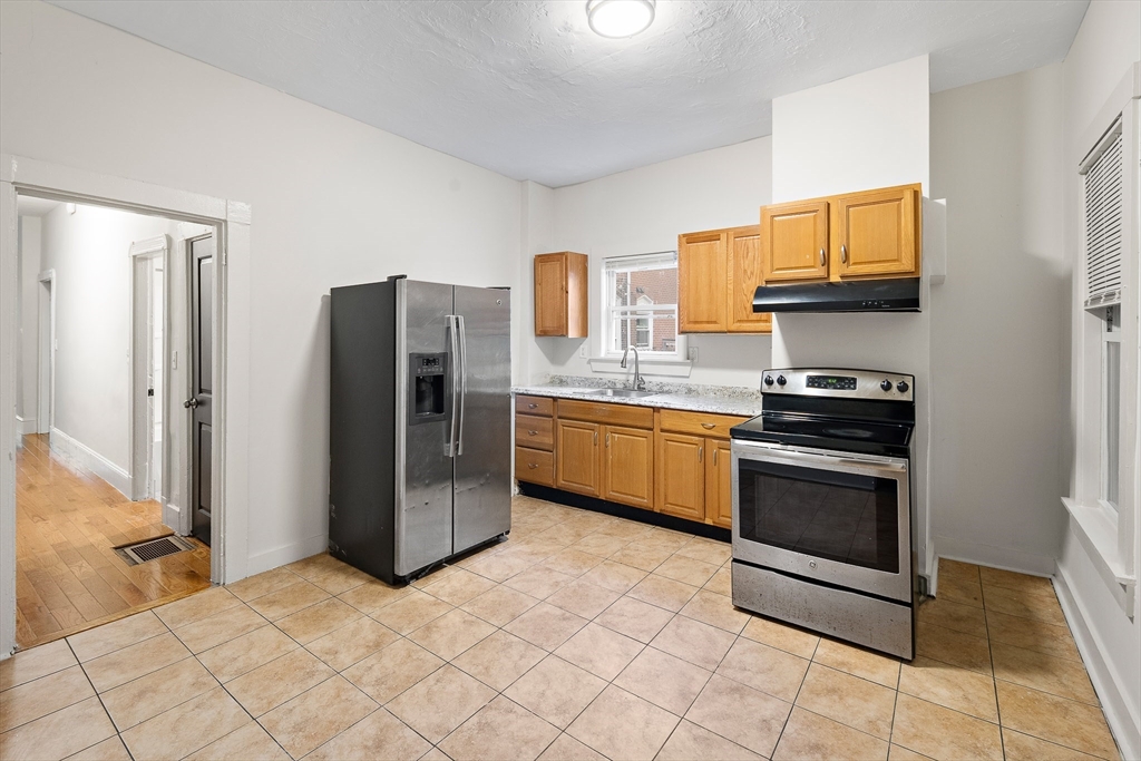 53 Copeland Street, Unit 2 Boston, MA 02119 - Photo 11 of 15 a kitchen with stainless steel appliances granite countertop a refrigerator stove and sink