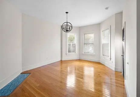a view of an empty room with window and wooden floor