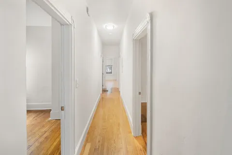 a view of a hallway with wooden floor and staircase