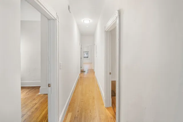 a view of a hallway with wooden floor and staircase