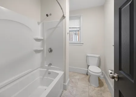 a white toilet sitting next to a bath tub