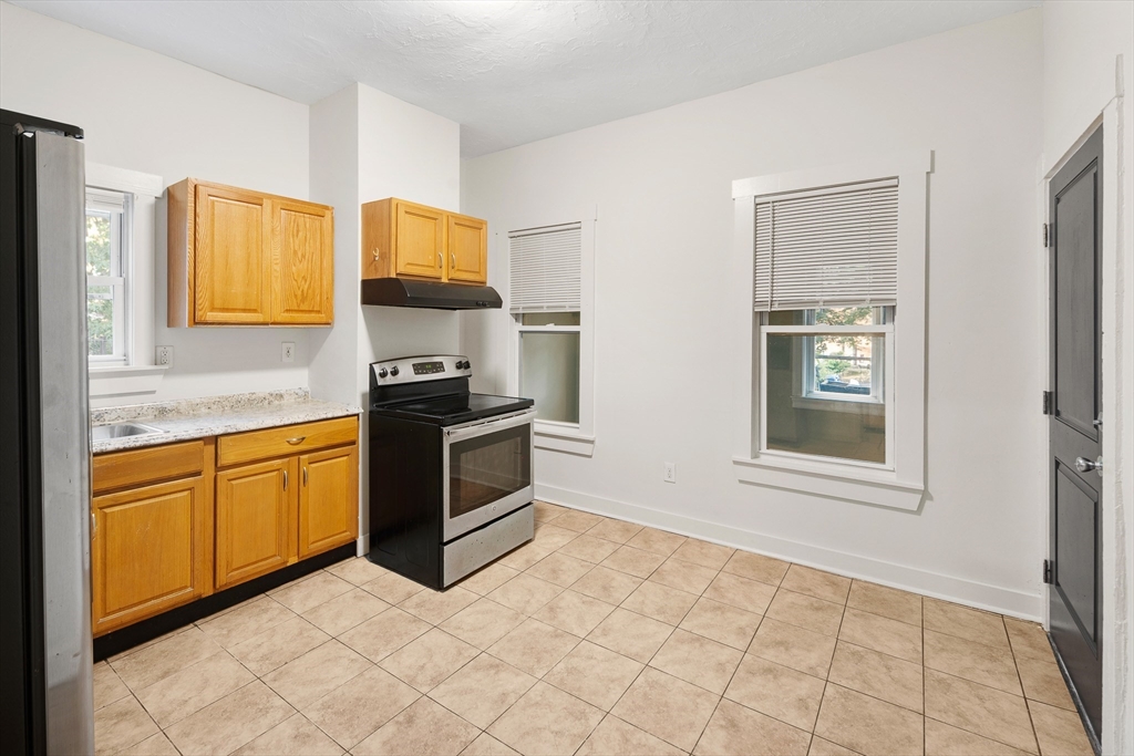 53 Copeland Street, Unit 2 Boston, MA 02119 - Photo 10 of 15 a kitchen with granite countertop a stove top oven microwave and cabinets