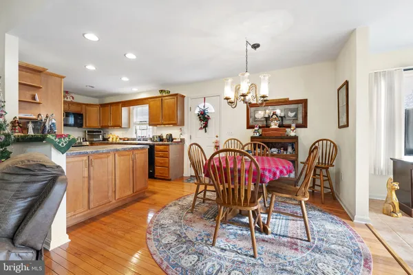 a kitchen with stainless steel appliances kitchen island granite countertop a dining table chairs and a refrigerator