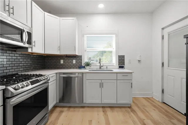 a kitchen with stainless steel appliances white cabinets and a stove top oven