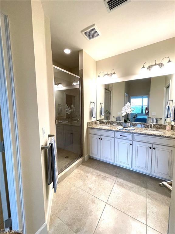 9426 Benvenuto Court, Unit 203 Naples, FL 34119 - Photo 26 of 42 a large bathroom with a glass door shower sink and mirror
