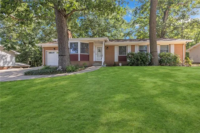 a view of a house with a yard and large trees