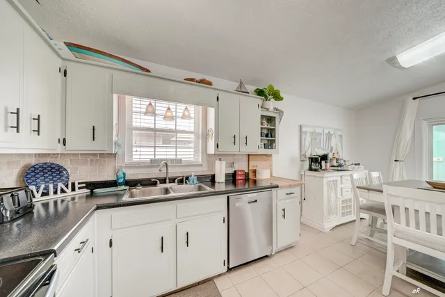 a kitchen with a sink white cabinets and window