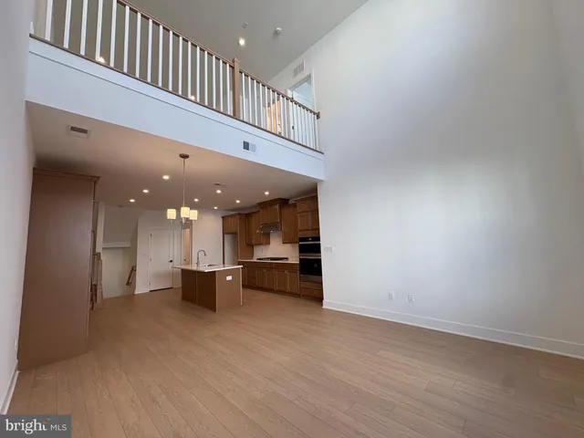 a big room with wooden floor and kitchen view