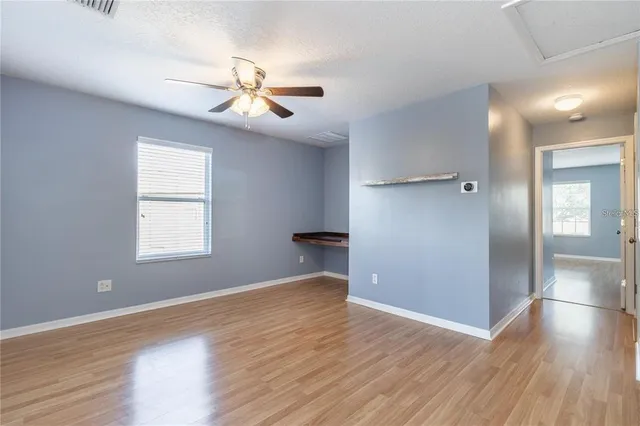 a view of empty room with wooden floor and fan