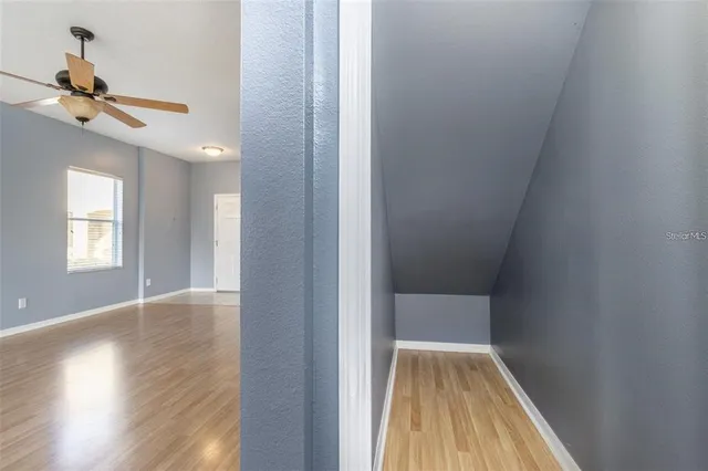 a view of hallway with wooden floor and ceiling fan