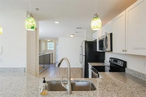 a kitchen with stainless steel appliances granite countertop a sink a stove and a refrigerator