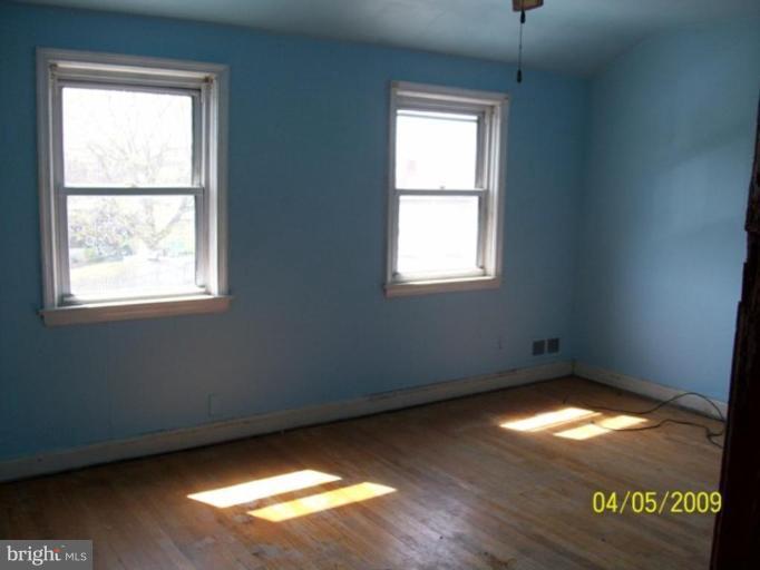 247 Orville Road Essex, MD 21221 - Photo 5 of 8 a view of an empty room with wooden floor and a window