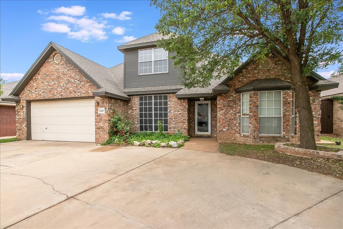 5307 69th Street Lubbock, TX 79424 - Photo 21 of 22 a front view of a house with a yard and a garage