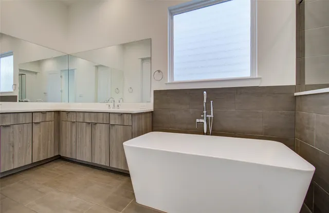 a bathroom with a double vanity sink a mirror and a bathtub