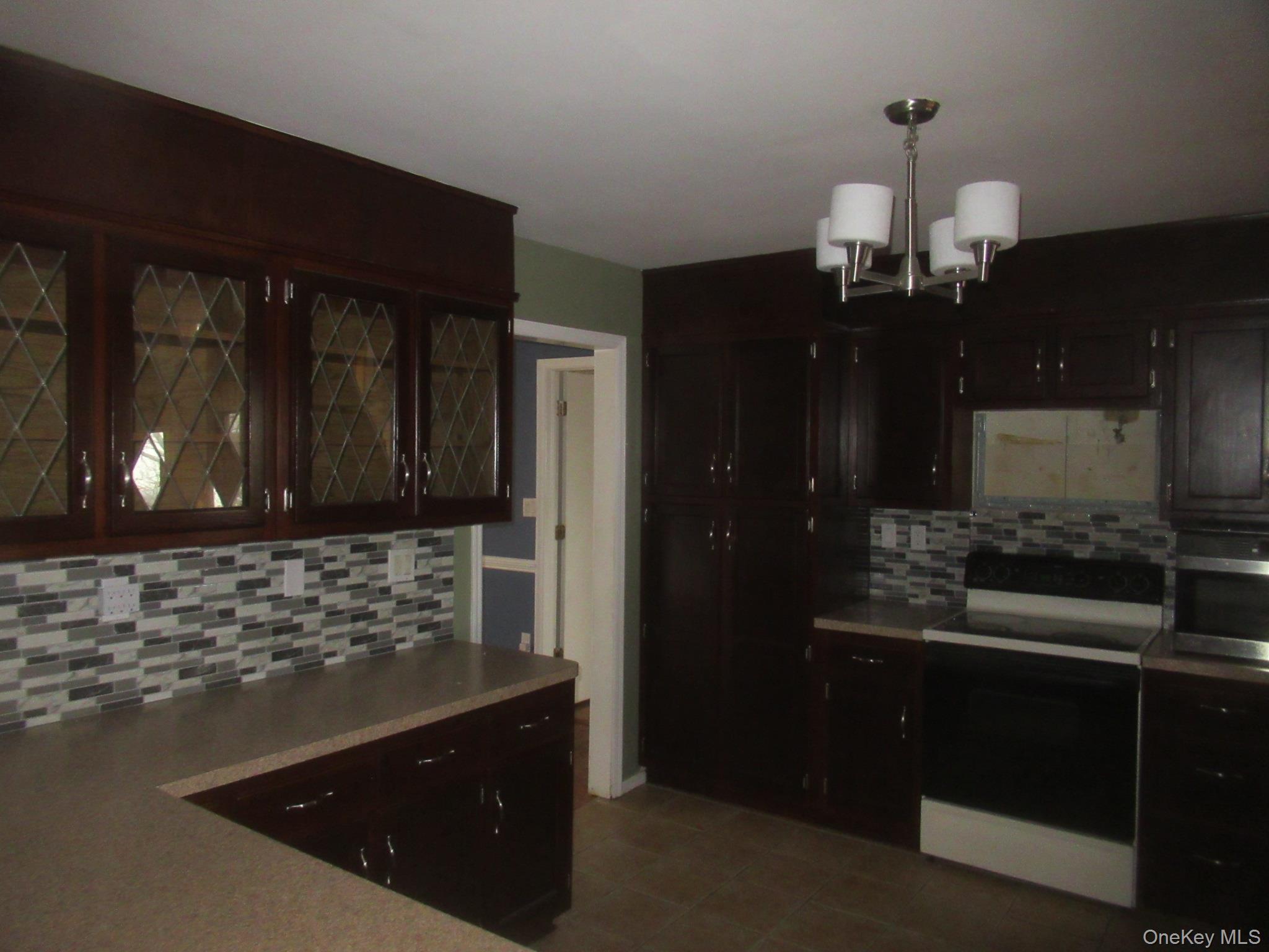 64 Hillside View Road Mahopac, NY 10541 - Photo 6 of 25 Kitchen featuring electric range oven, tasteful backsplash, a chandelier, pendant lighting, and stainless steel microwave