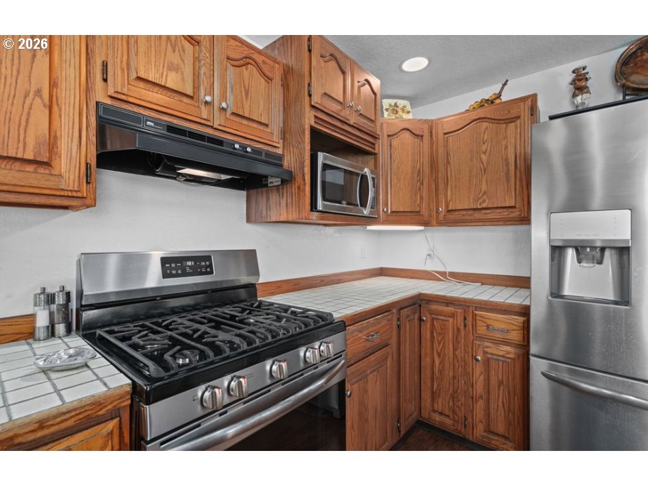 406 West C Street Rainier, OR 97048 - Photo 22 of 48 a kitchen with stainless steel appliances granite countertop a stove and a refrigerator