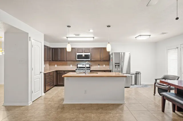 a kitchen with stainless steel appliances a stove top oven a sink a refrigerator and cabinets
