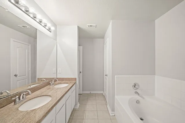 a bathroom with a granite countertop tub sink and mirror