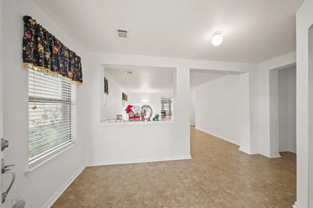 a view of an empty room with painting on the wall and a window