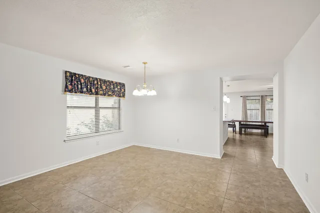 an empty room with chandelier and windows