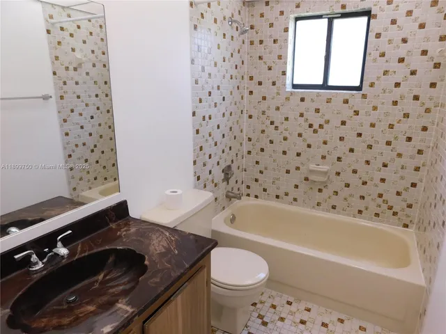 a bathroom with a granite countertop toilet a sink and a bathtub