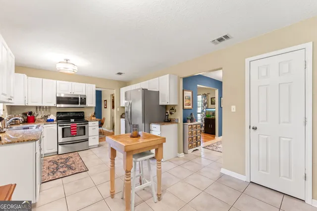 a spacious bedroom with a bed a dresser and wooden floor