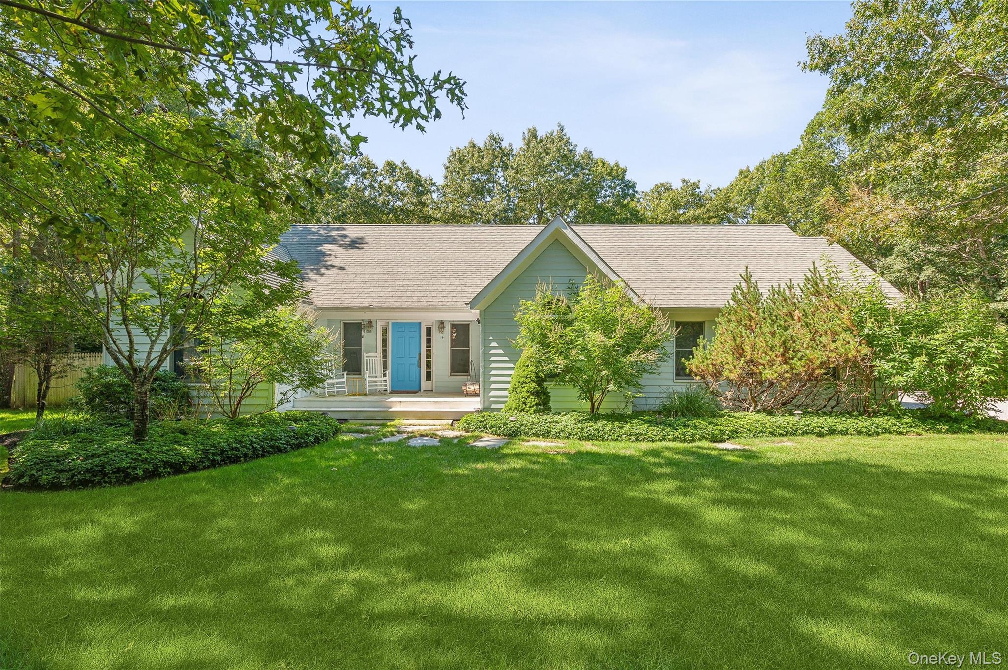a view of a house with a big yard and potted plants and large tree