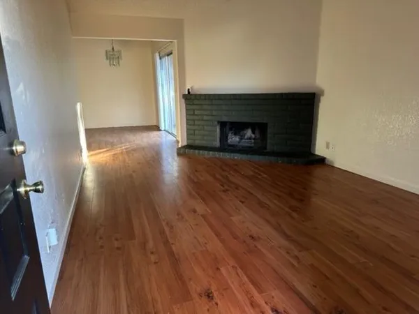 a view of a livingroom with wooden floor and a fireplace