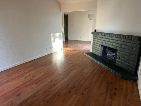 a view of empty room with wooden floor and fireplace