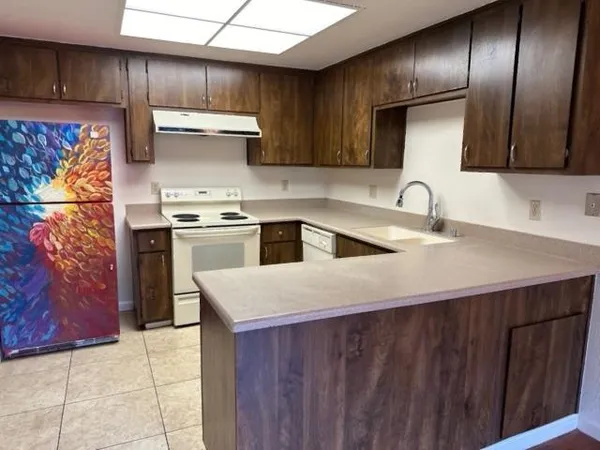 a kitchen with stainless steel appliances granite countertop a sink a stove and a wooden cabinets