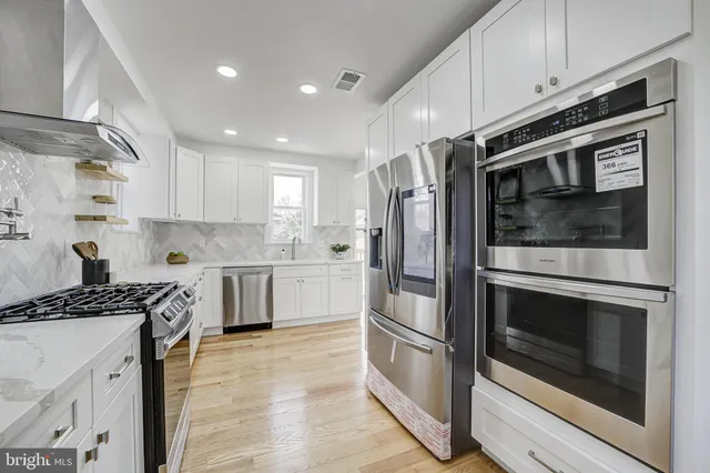 a kitchen with stainless steel appliances white cabinets a stove a sink and a microwave