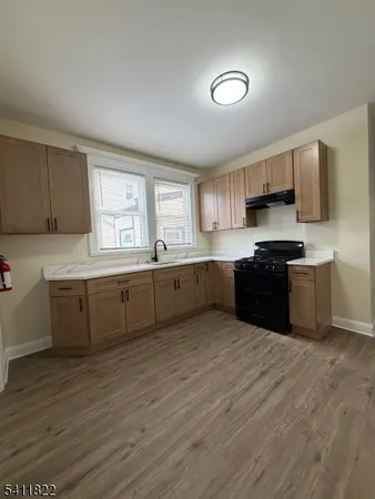 a large kitchen with stainless steel appliances granite countertop a sink cabinets and wooden floor