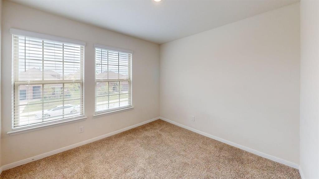 1306 Colonial Bluff Lane Princeton, TX 75407 - Photo 10 of 27 Neutral tone walls with white trim, two double-hung windows featuring blinds, and light brown carpeting