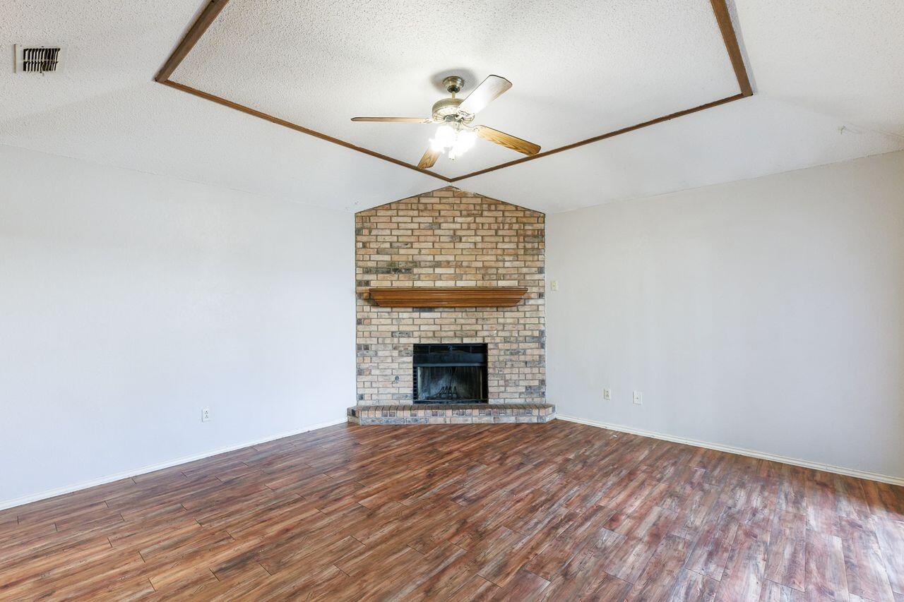 6411 York Drive, Unit B Lubbock, TX 79414 - Photo 7 of 28 a view of an empty room with wooden floor fireplace and a window