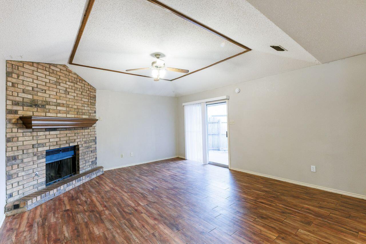 6411 York Drive, Unit B Lubbock, TX 79414 - Photo 10 of 28 a view of an empty room with wooden floor fireplace and a window