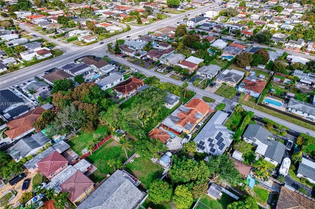 an aerial view of residential houses with outdoor space and trees all around