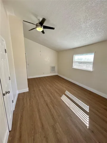 an empty room with wooden floor fan and windows