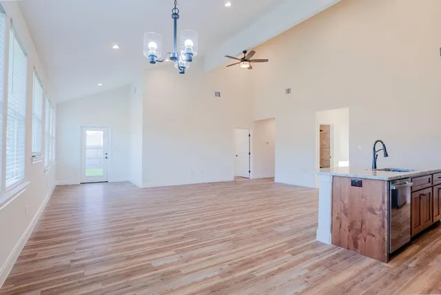 a view of an empty room with wooden floor and a chandelier