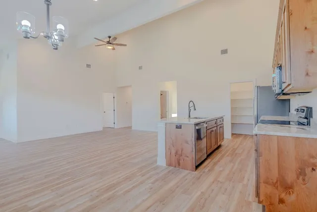 a kitchen with stainless steel appliances granite countertop a sink dishwasher and a stove with wooden floor