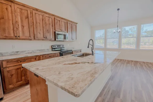 a kitchen with stainless steel appliances granite countertop a kitchen island a stove and a sink