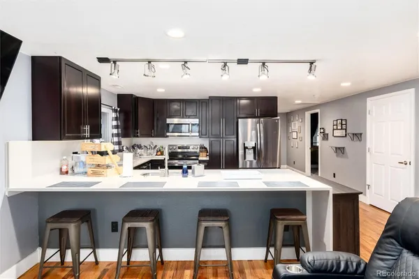 a kitchen with stainless steel appliances kitchen island granite countertop a table chairs sink and cabinets