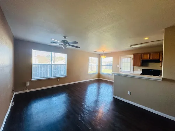 an empty room with wooden floor and windows